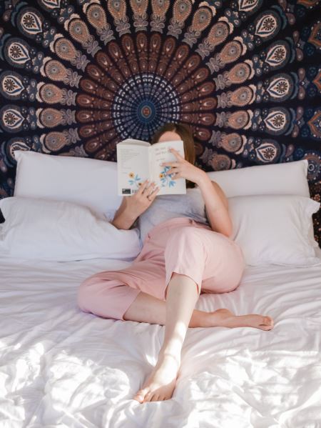 Girl reading a book on a bed